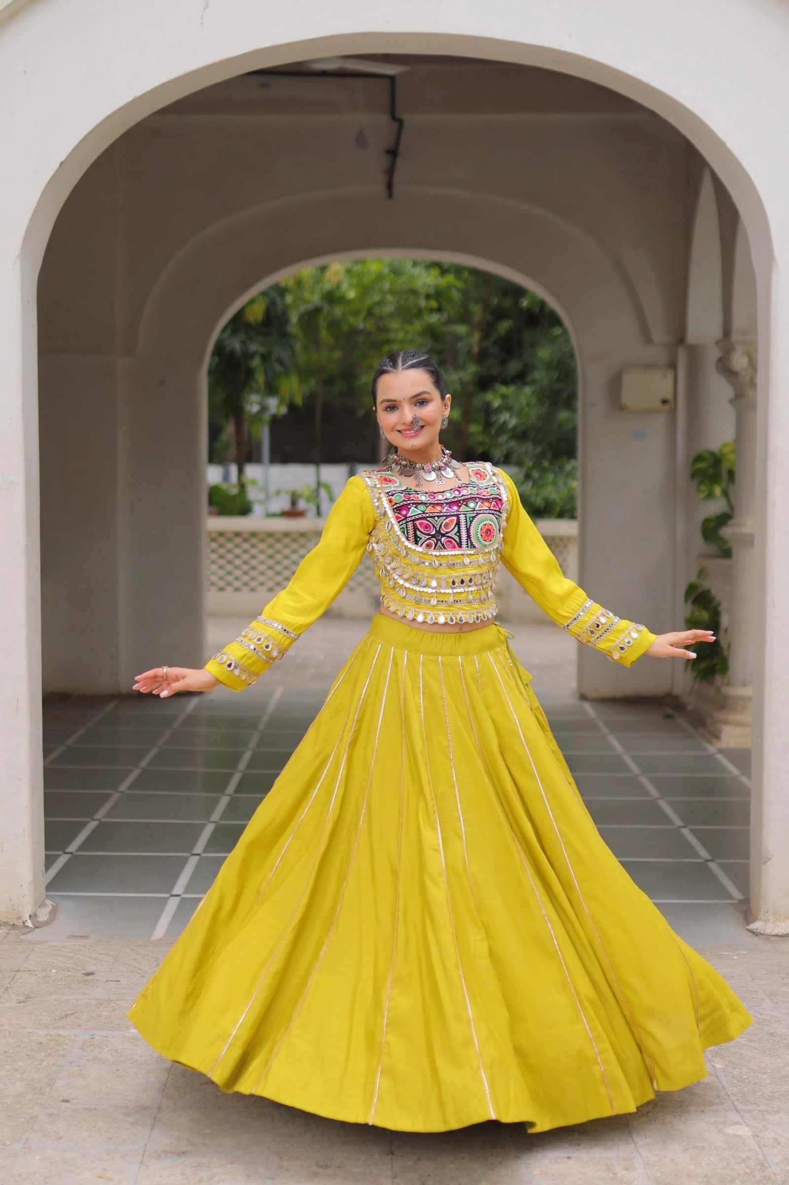 Woman in a yellow traditional outfit standing in an archway.