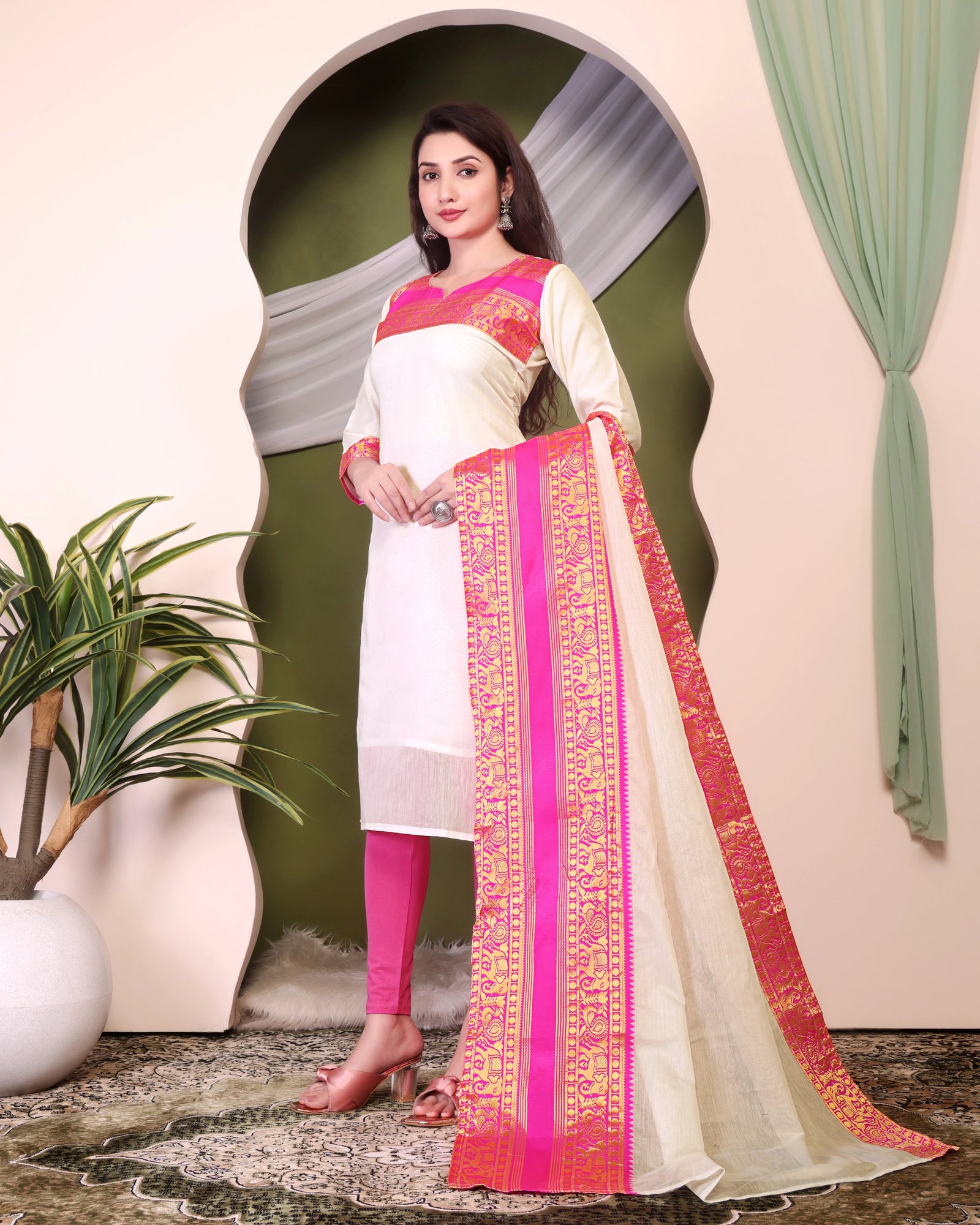 Woman wearing a traditional outfit with white and pink design, standing indoors.