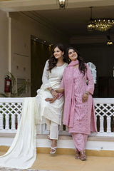 Two women in traditional attire standing on a staircase indoors.