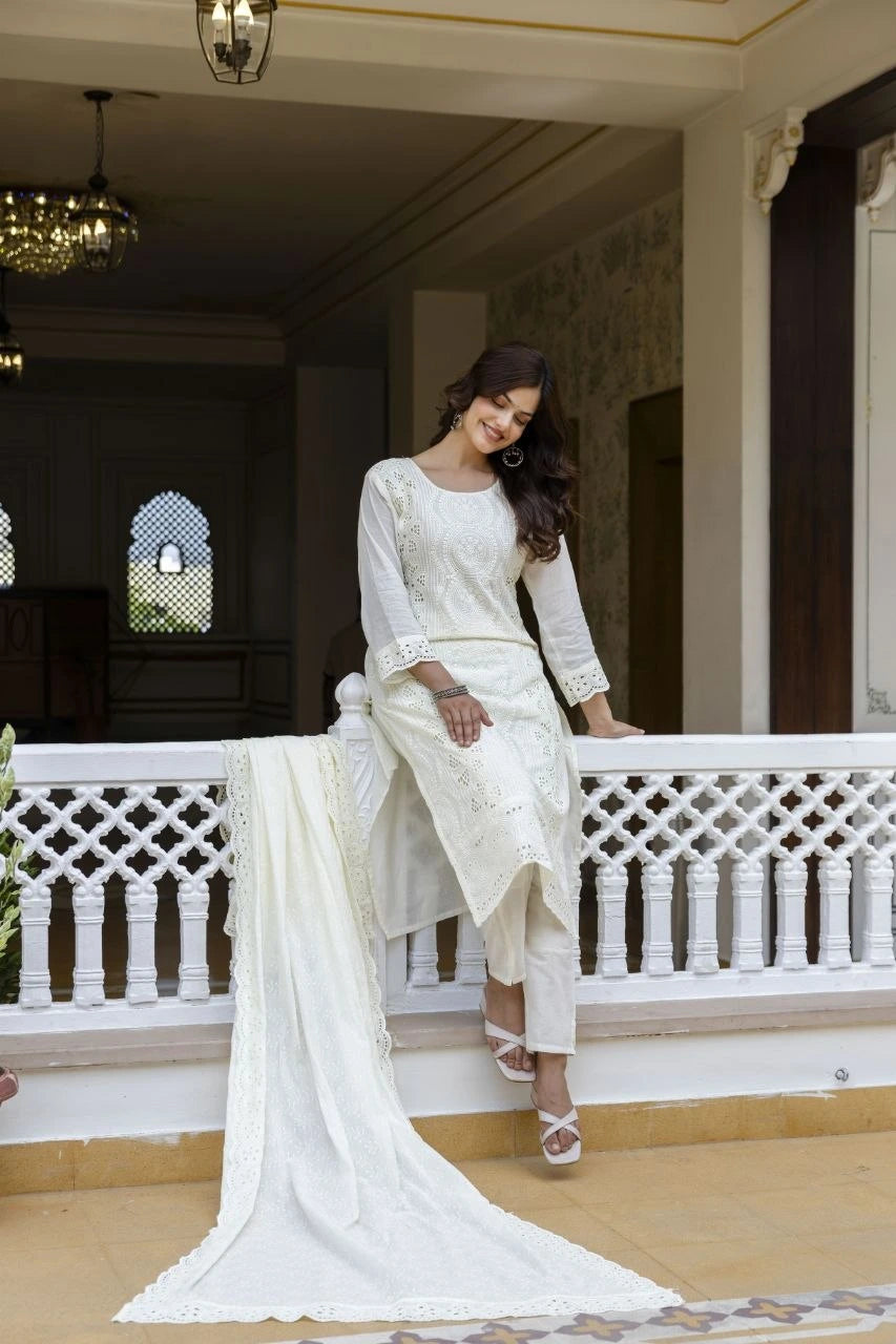 Woman in a white traditional outfit standing on a balcony with decorative railings.