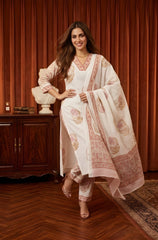 Woman in a traditional outfit standing in a room with wooden floor and furniture.