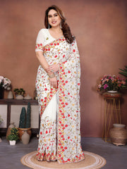 Woman wearing a floral saree in a decorated room with plants and vases.