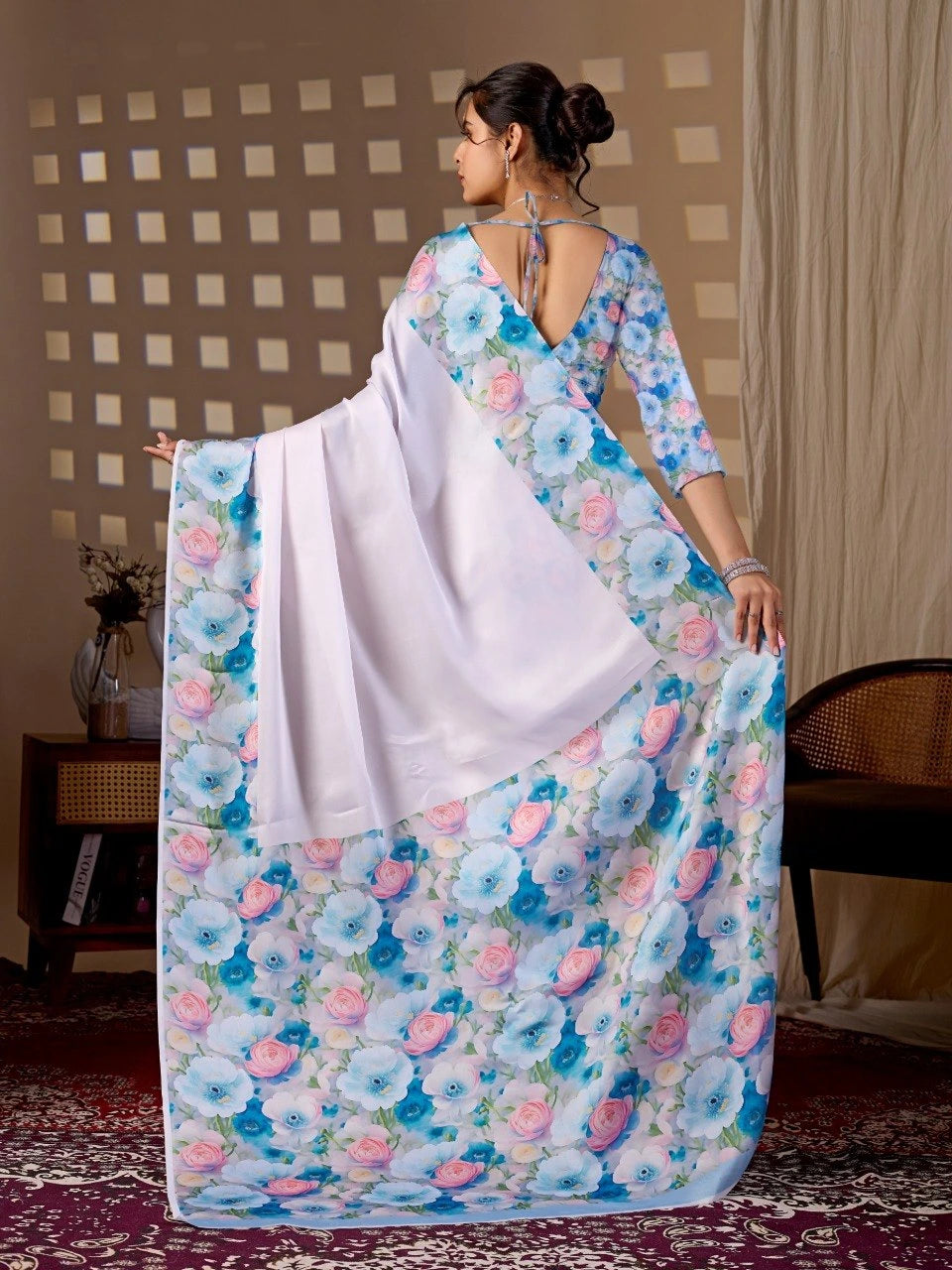 Woman wearing a floral saree with a white blouse in a room setting.