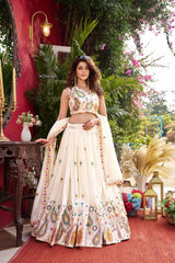 Woman in a traditional outfit with floral patterns standing in an outdoor setting with plants and flowers.