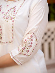 Close-up of a white blouse with floral embroidery on a blurred background