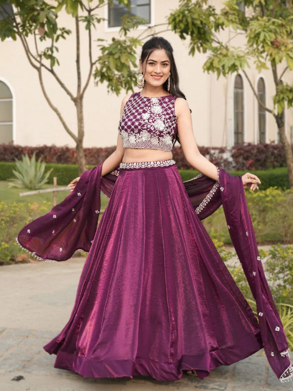 Woman in a purple traditional outfit with a matching dupatta outdoors.