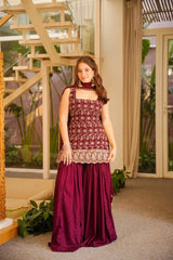 Woman in a maroon traditional outfit standing indoors with decorative elements.