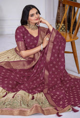 Woman wearing a maroon saree with a white blouse, sitting on a wooden chair.