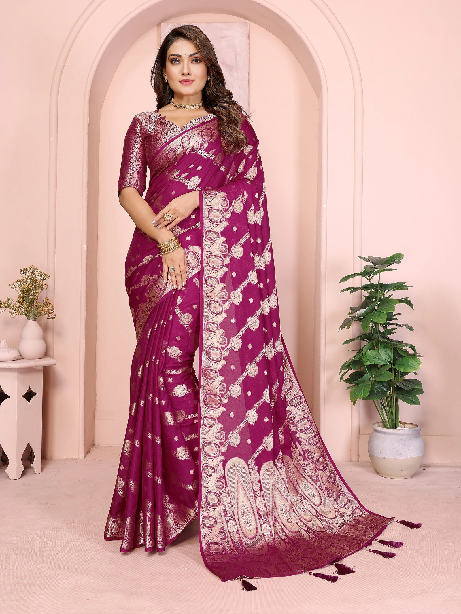 Woman wearing a purple saree with white patterns in an elegant indoor setting.