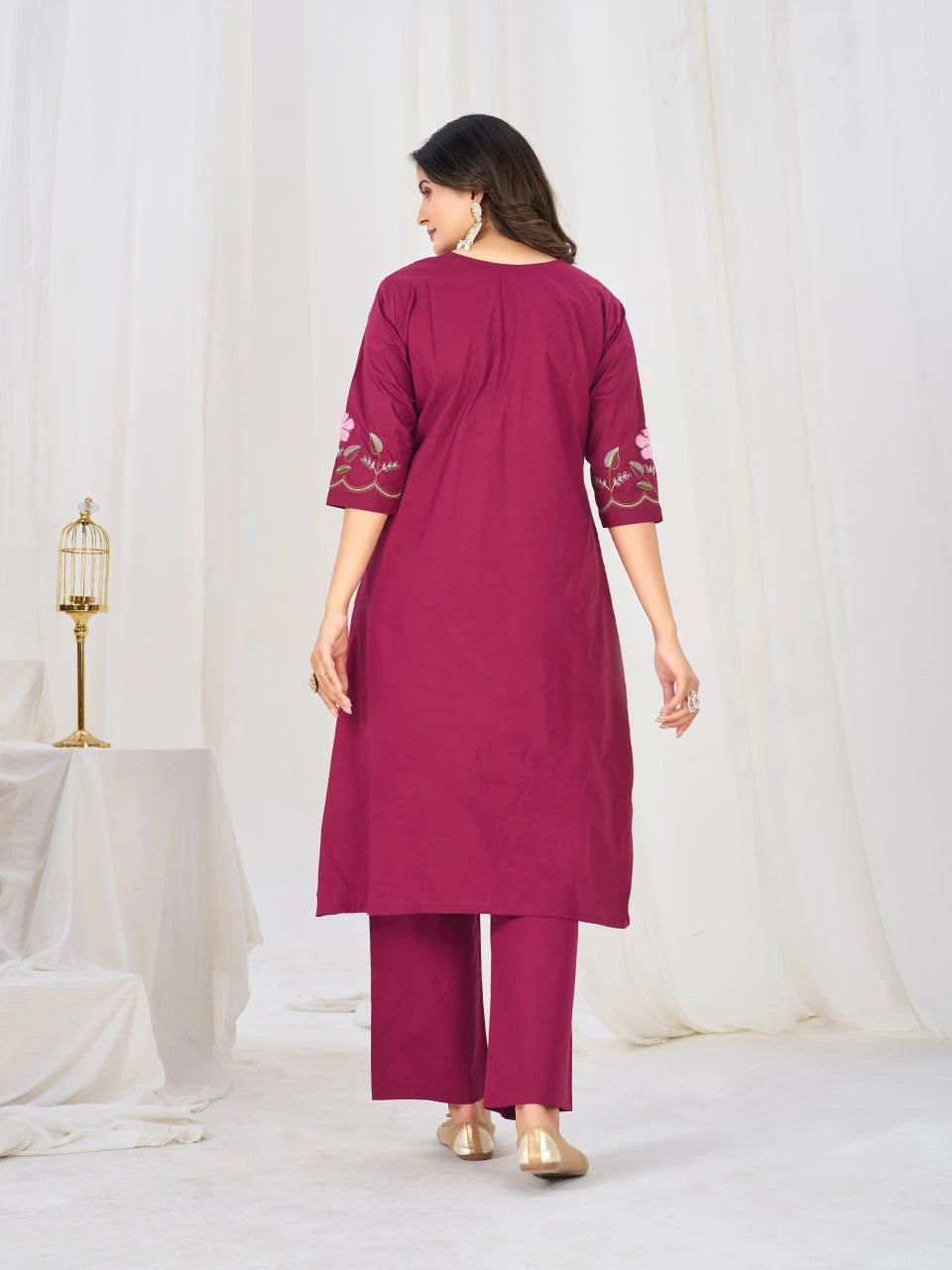 Woman wearing a magenta kurta with white embroidery on a white background