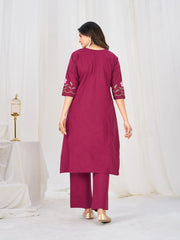 Woman wearing a magenta kurta with white embroidery on a white background