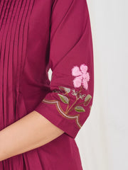 Maroon pleated dress with floral embroidery on a white background