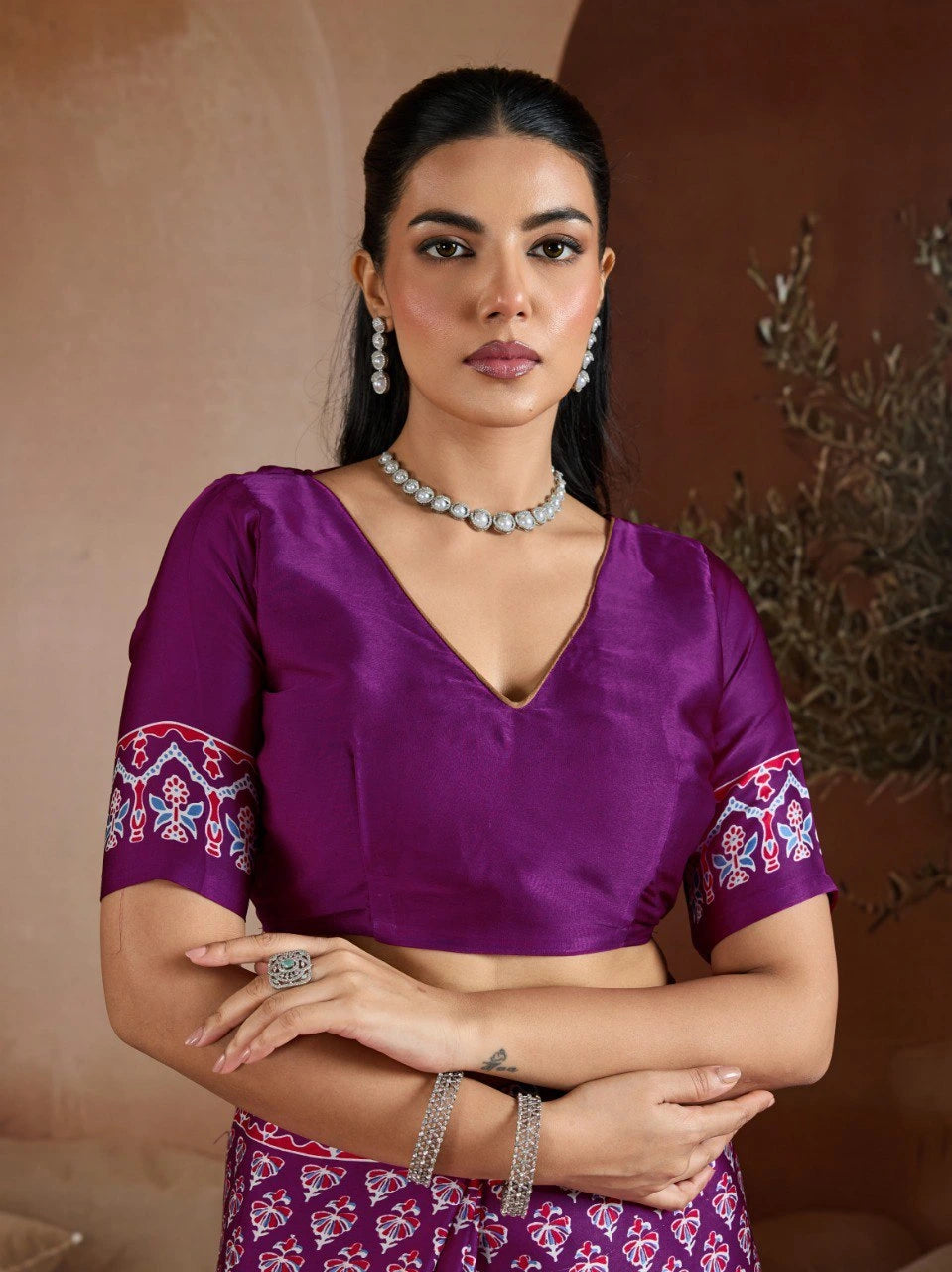Woman wearing a purple blouse with floral sleeves and a matching skirt against a neutral background