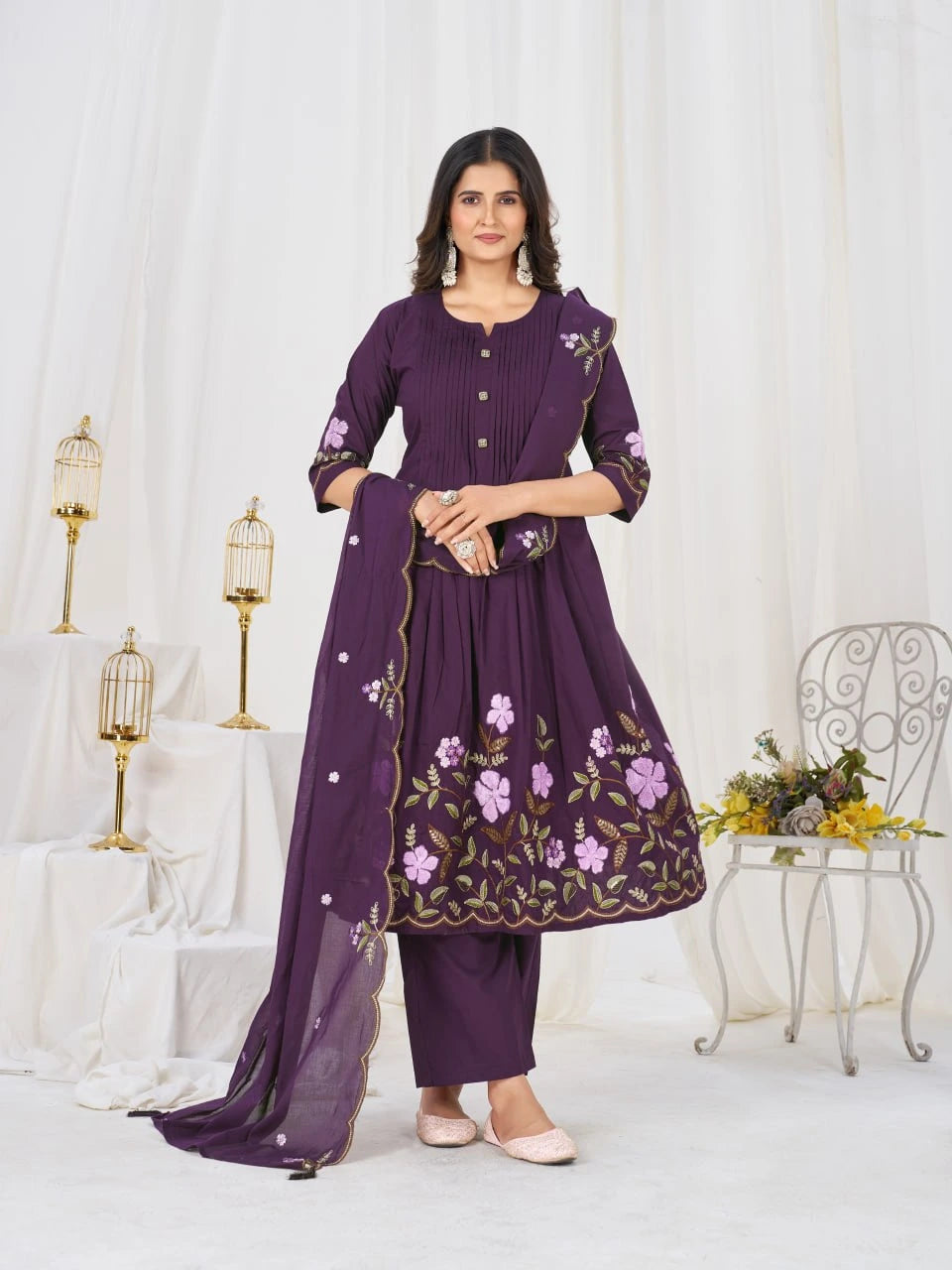 Woman wearing a purple embroidered outfit in a decorated room.