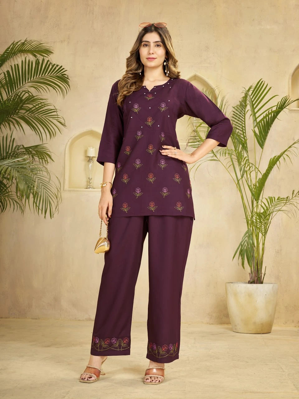 Woman wearing a purple traditional outfit with a beige background and plants.