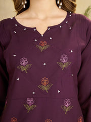 Close-up of a purple garment with floral embroidery and bead details.