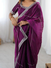 Purple saree with silver border being held by a person against a white background