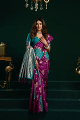 Woman in a purple and blue saree standing on a dark staircase.
