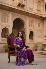 Woman in a purple saree sitting on a ornate chair in front of an architectural building.