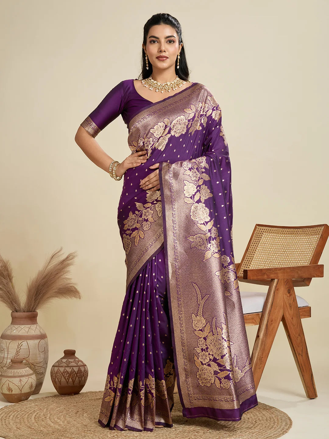 Woman wearing a purple saree with gold patterns against a beige background