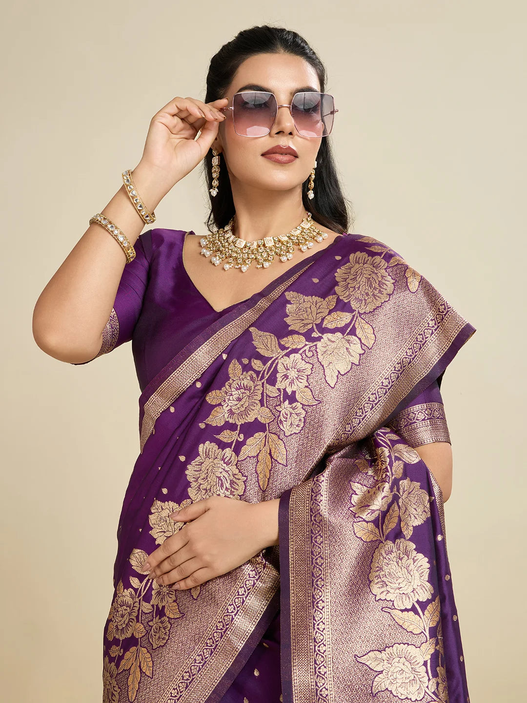Woman wearing a purple saree with floral patterns on a beige background