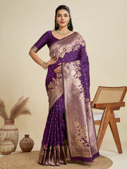 Woman wearing a purple saree with gold patterns against a beige background