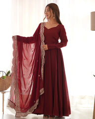 Woman wearing a maroon traditional outfit with a matching dupatta in a bright room.