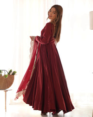 Woman wearing a long red dress with a matching shawl indoors.