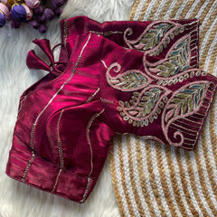 Maroon embroidered blouse on a textured surface with flowers in the background