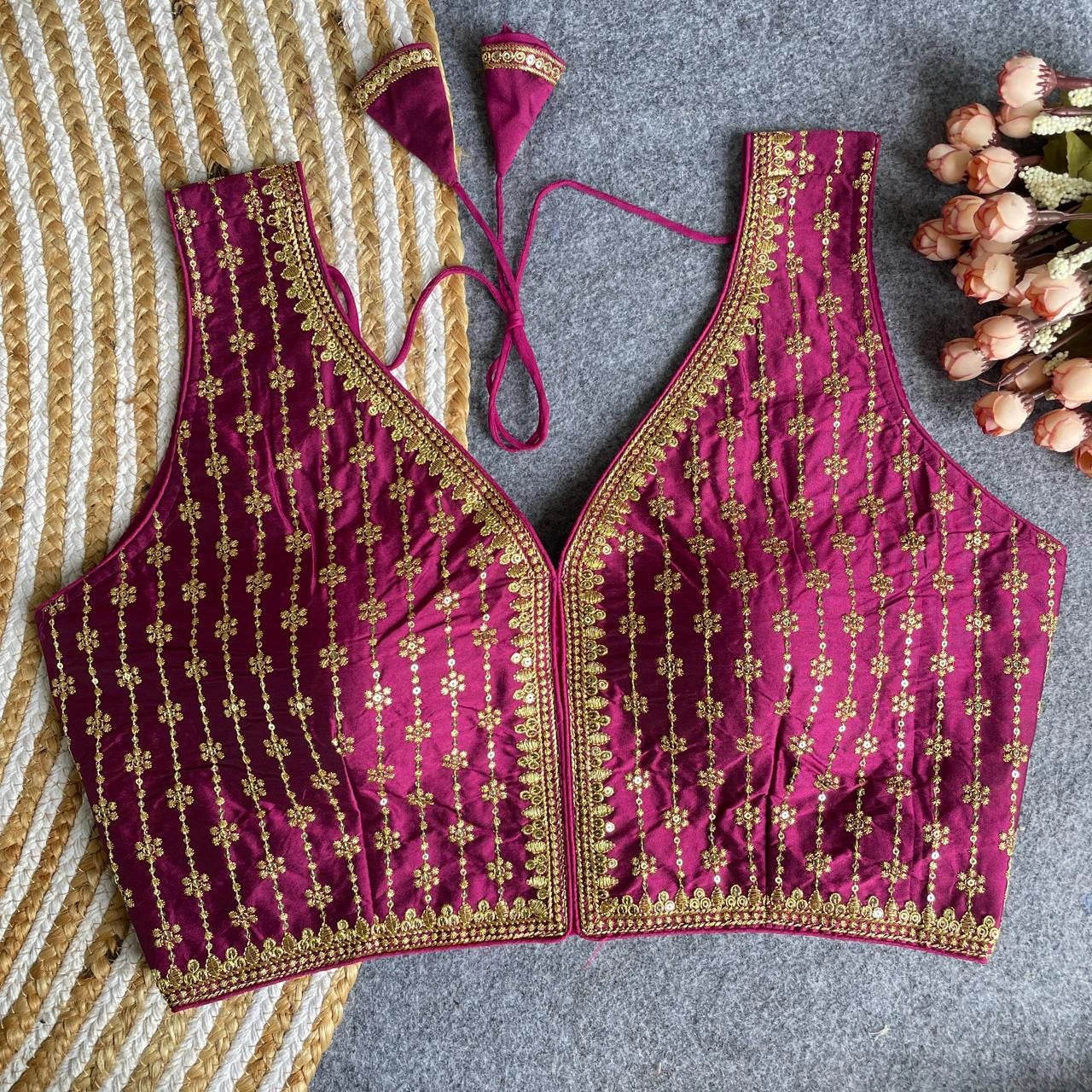 Maroon embroidered blouse with gold details on a textured surface