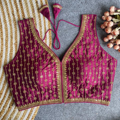 Maroon embroidered blouse with gold details on a textured surface