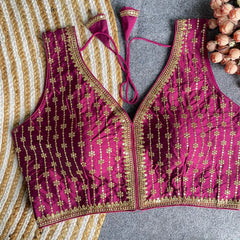 Pink embroidered blouse with gold details on a striped fabric background