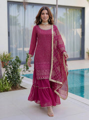 Woman in a pink traditional outfit standing by a poolside.