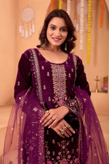 Woman wearing a purple embroidered traditional outfit with a beige background