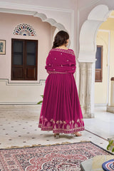 A full-length back view of the woman standing in a courtyard, highlighting the heavy pleating of the Anarkali that adds fullness to the skirt. The dupatta is wrapped around her back, showing the consistent gold floral buttis and border.