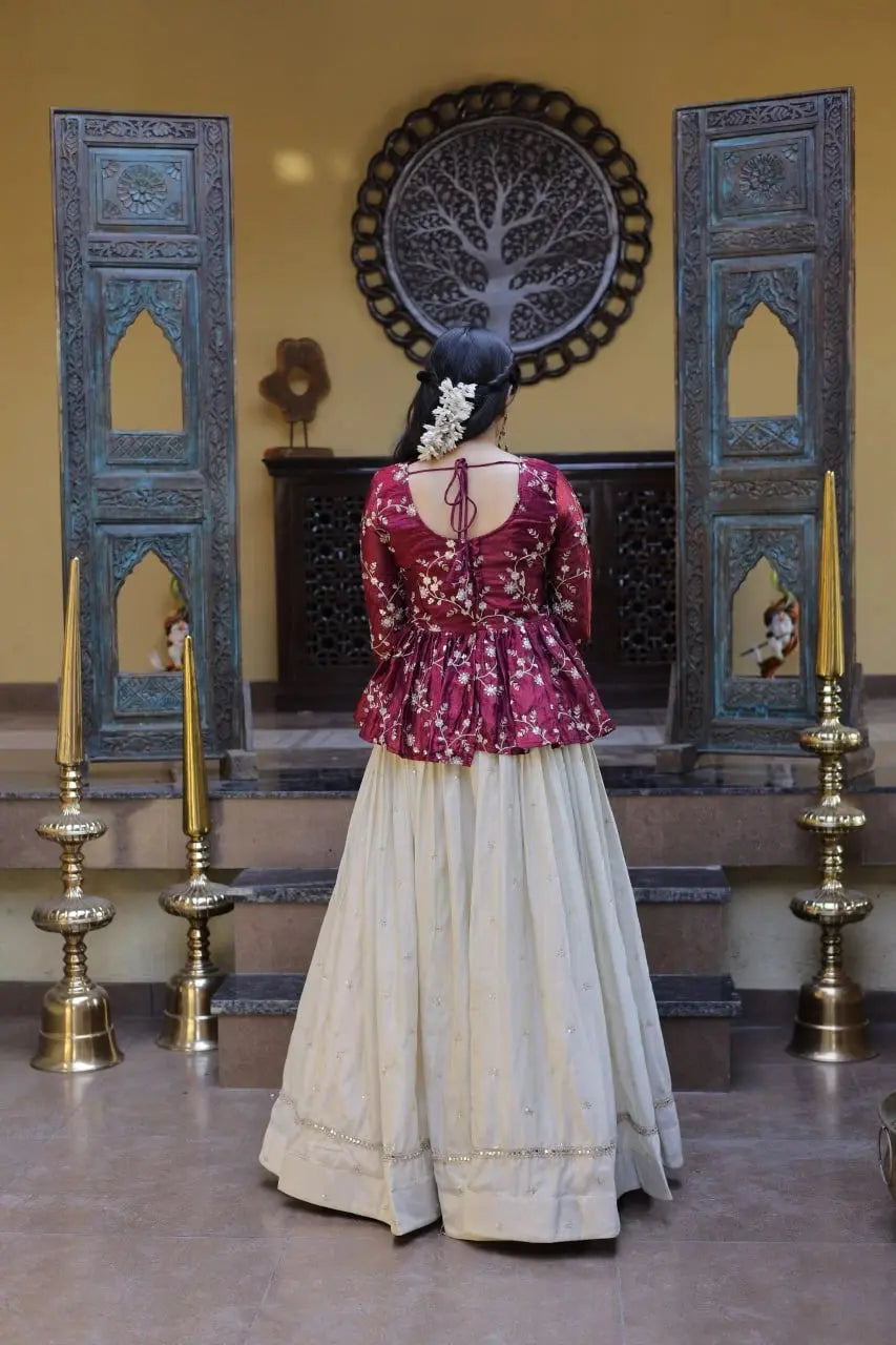 Woman in a traditional outfit standing in a decorated room with ornate doors and wall art.