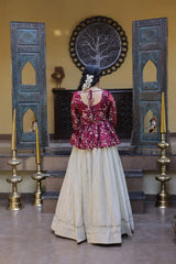 Woman in a traditional outfit standing in a decorated room with ornate doors and wall art.