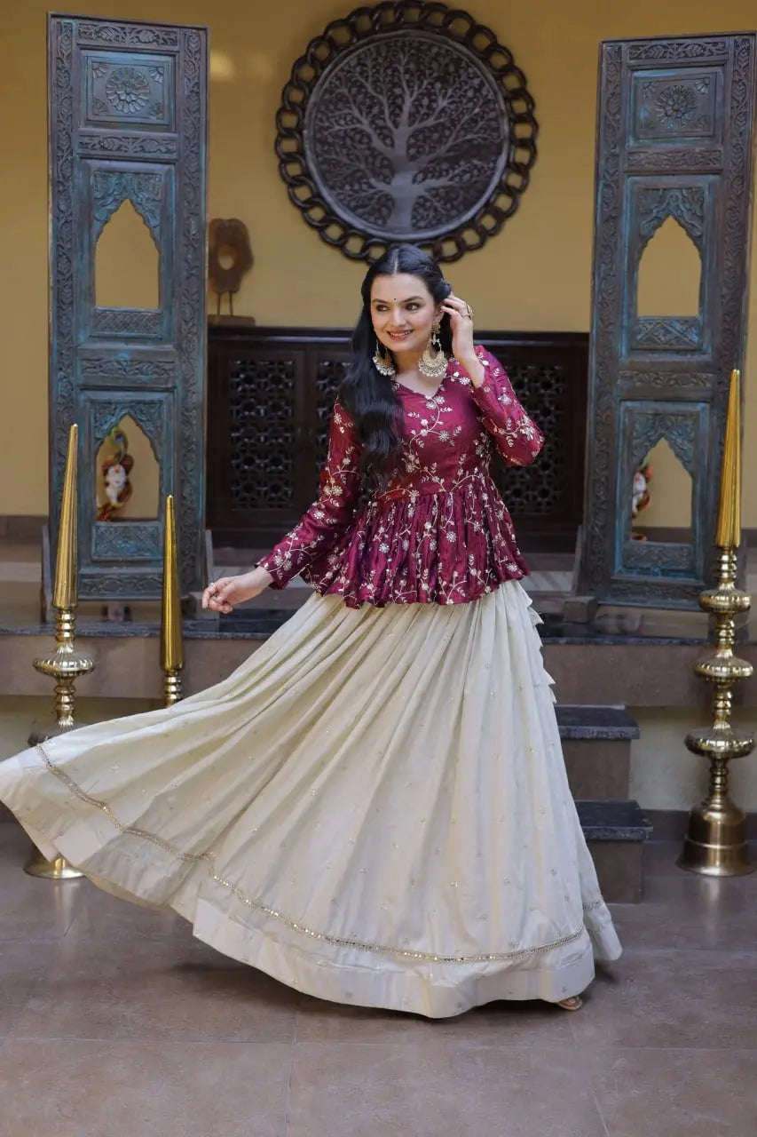 Woman in traditional outfit with maroon top and white skirt in a decorated room.