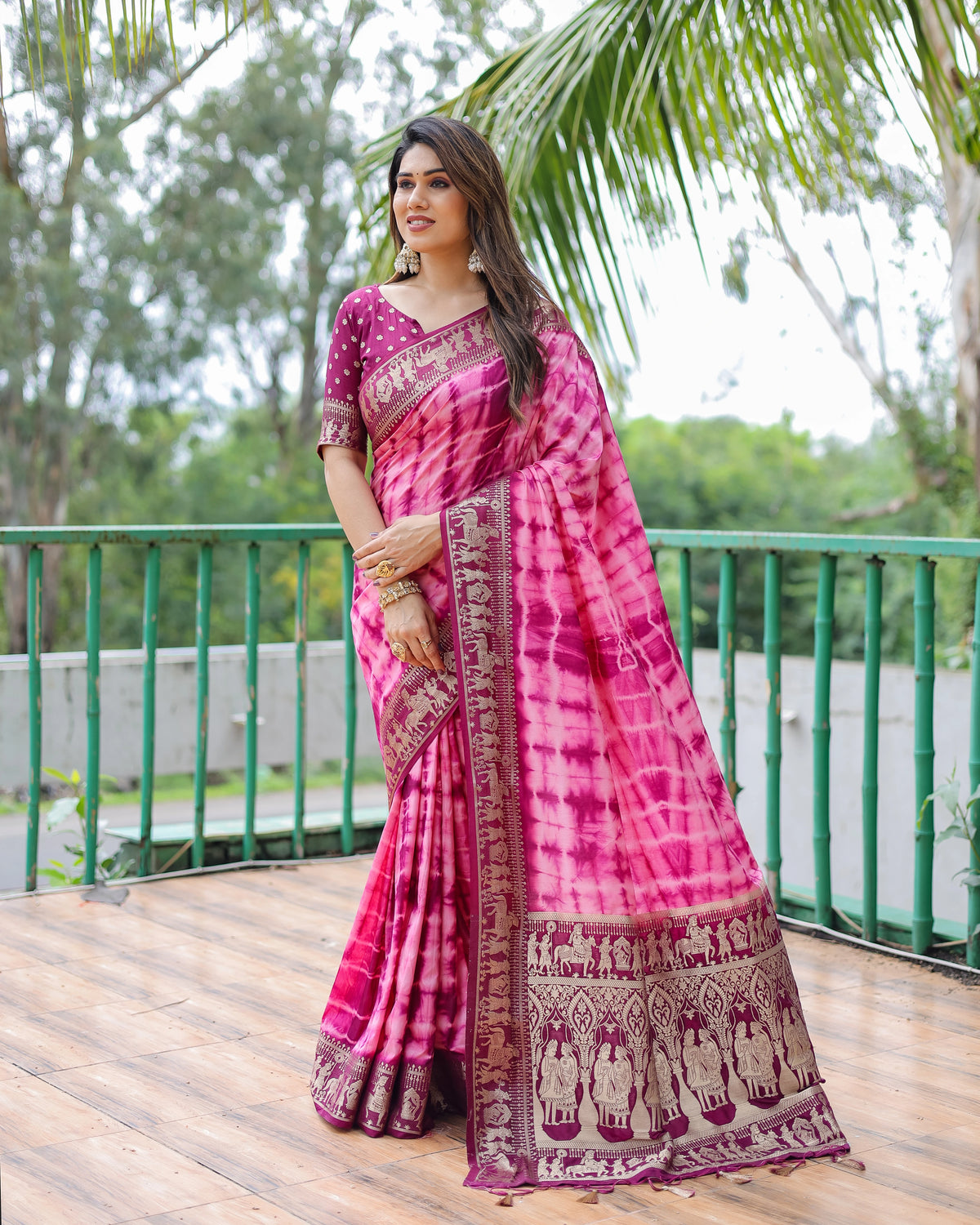 Woman wearing a pink saree with a green outdoor background