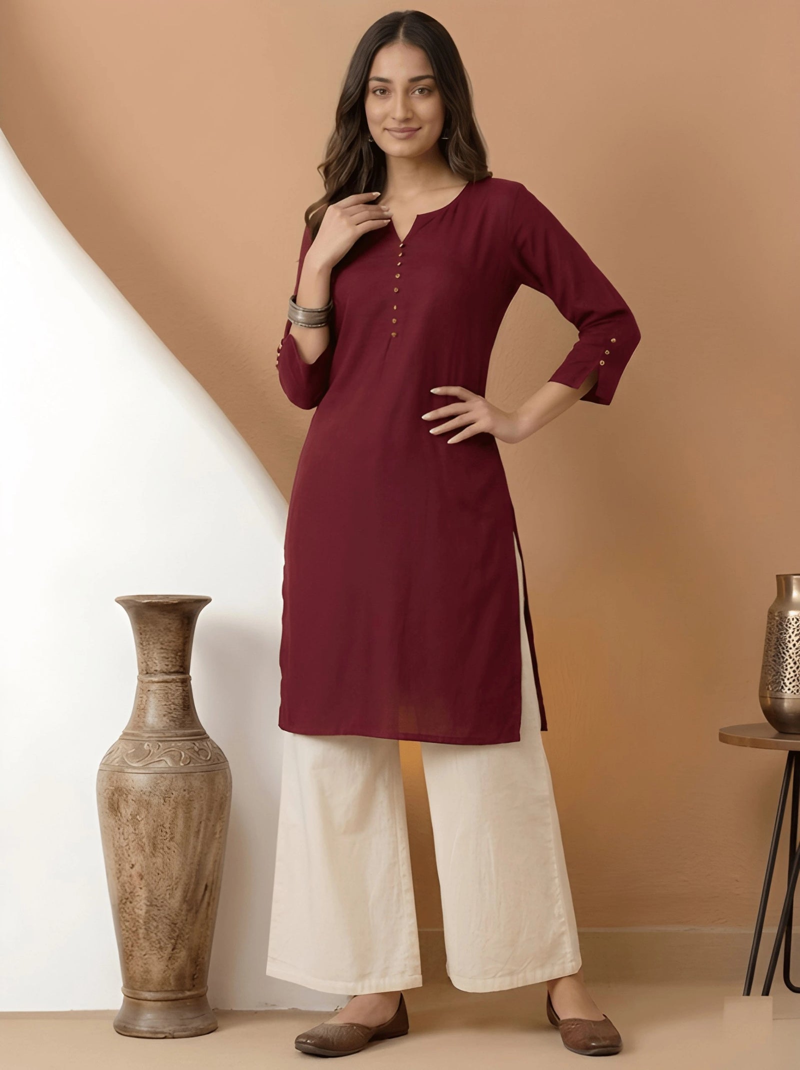 Woman wearing a maroon kurta with white pants against a beige background