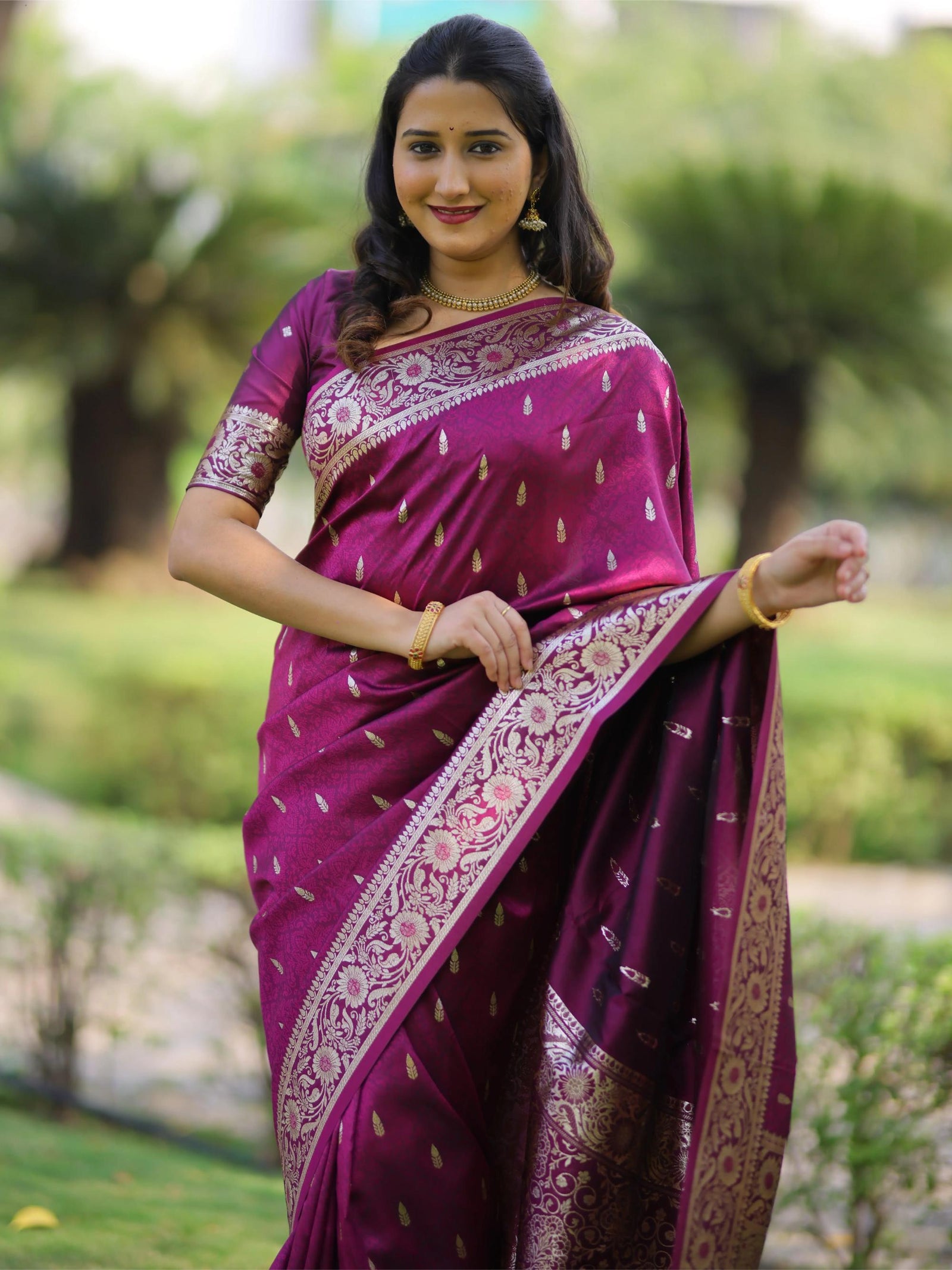 Woman wearing a purple saree with a floral blouse in an outdoor setting