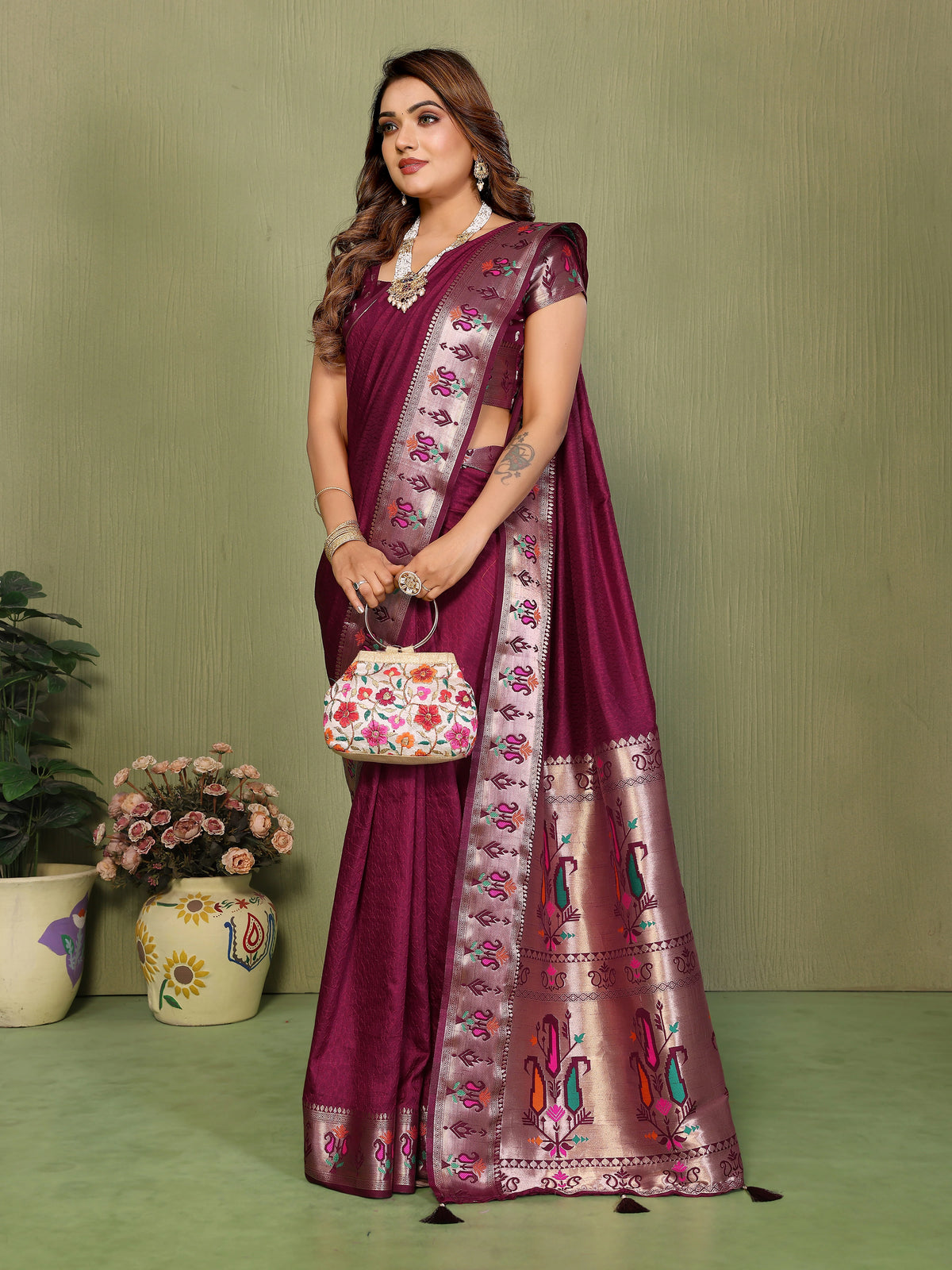 Woman wearing a maroon saree with floral patterns against a green background