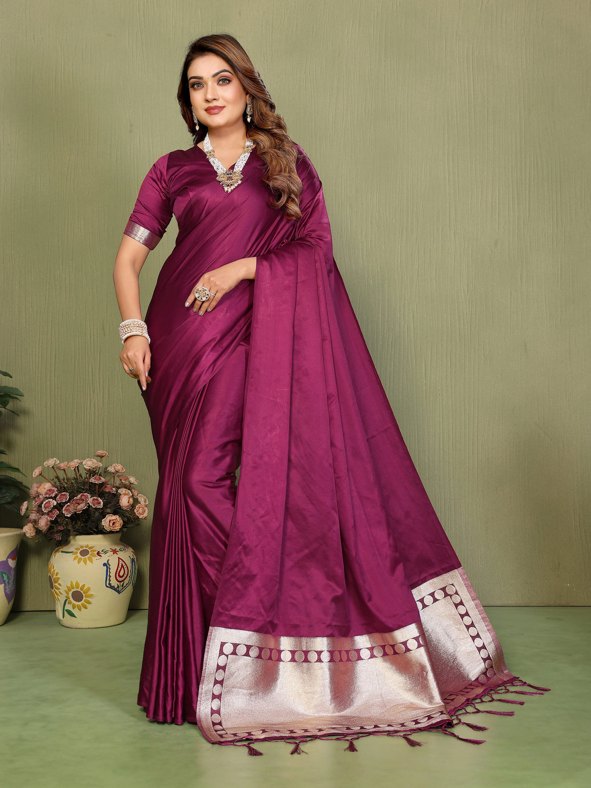 Woman wearing a purple saree with a white border on a green background