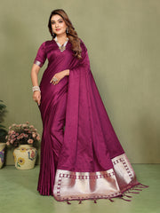 Woman wearing a purple saree with a white border on a green background