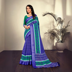 Woman in a traditional navy blue saree with printed patterns standing indoors near a potted plant