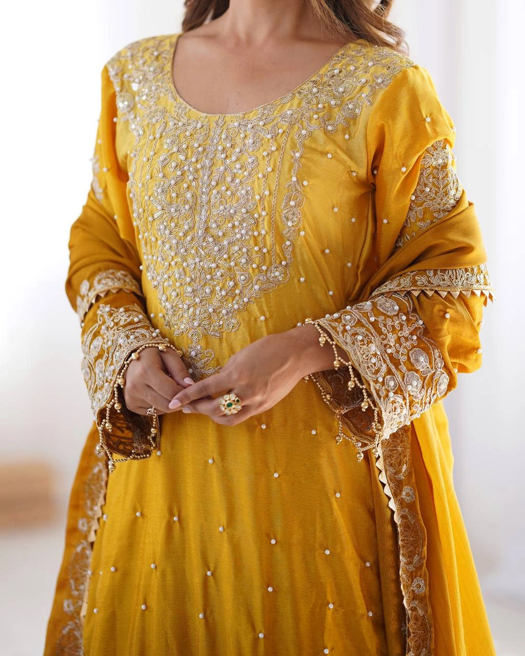 Yellow embroidered traditional outfit with gold details on a white background