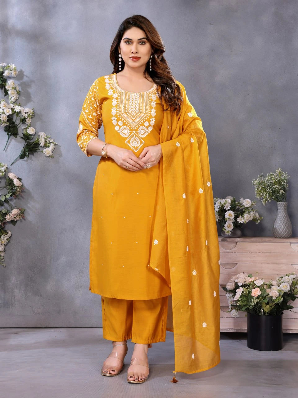 Woman in a yellow traditional outfit with floral decorations against a gray background