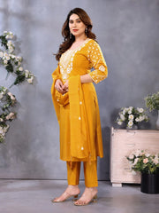 Woman in a yellow traditional outfit standing against a gray background with decorative elements.