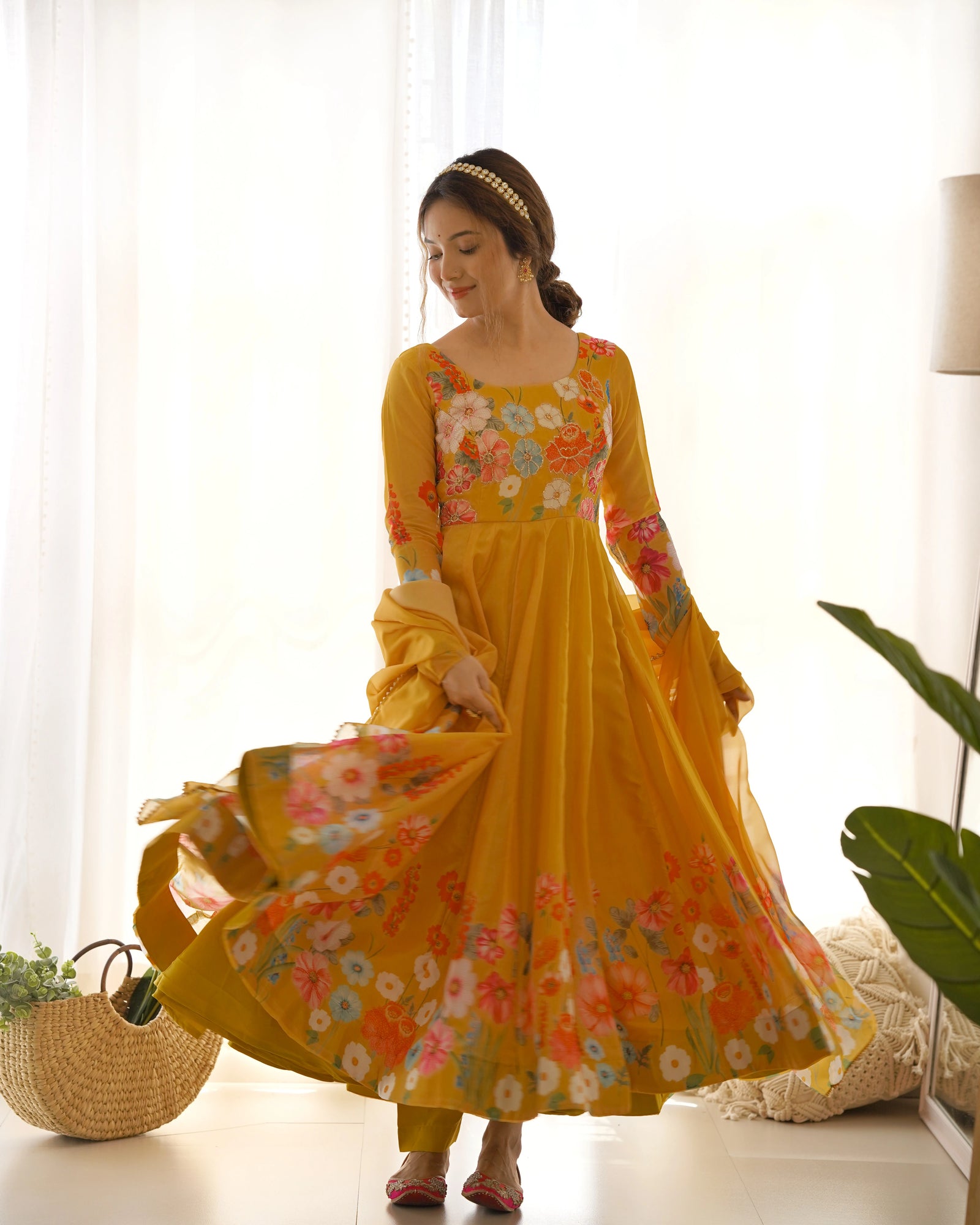 Woman in a yellow floral dress standing in a bright room with white curtains.