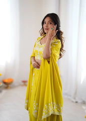 Woman wearing a yellow traditional outfit with a white embroidered border indoors.